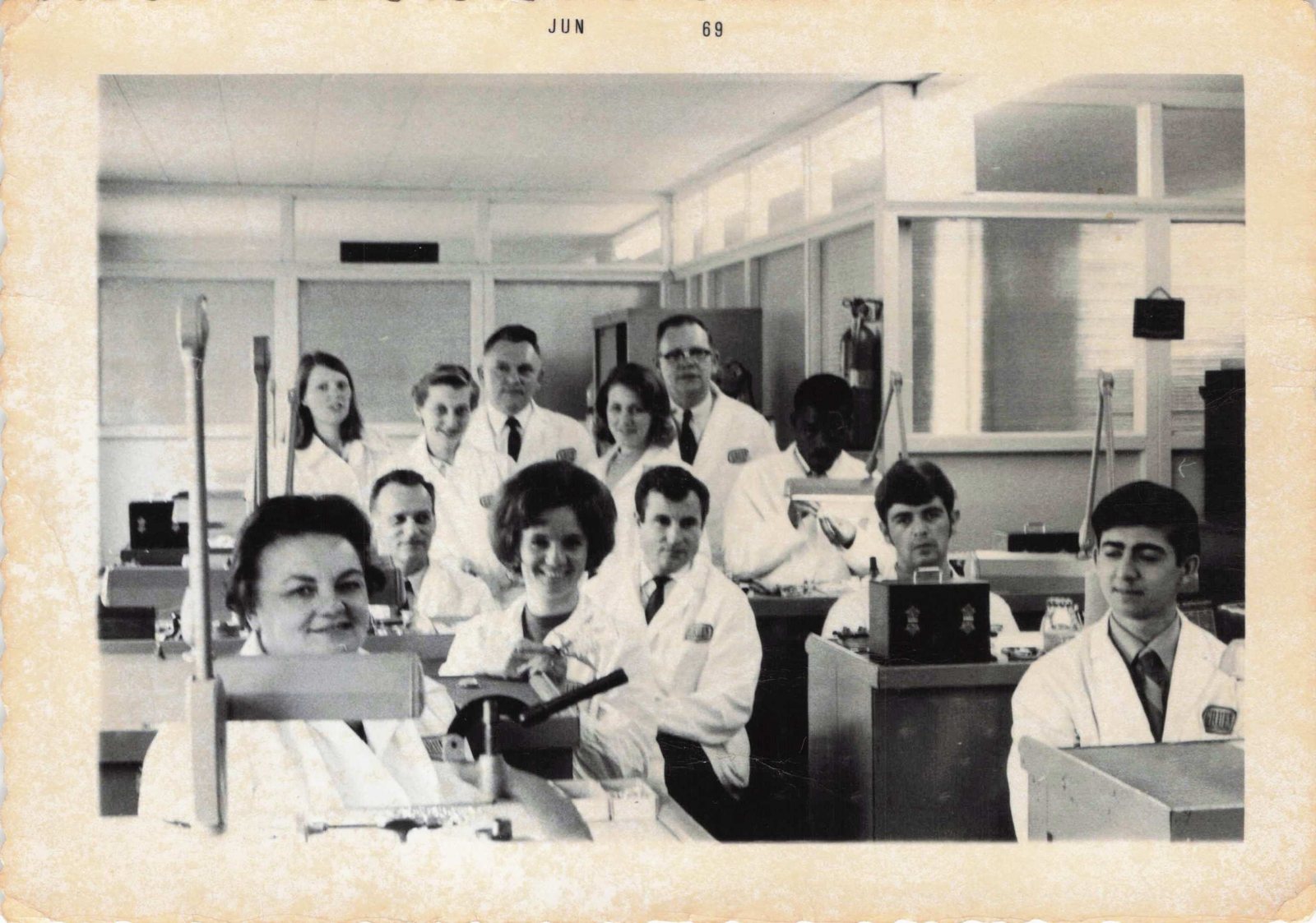 Watchmakers in white coats at their benches in a workshop, photo dated June 1969